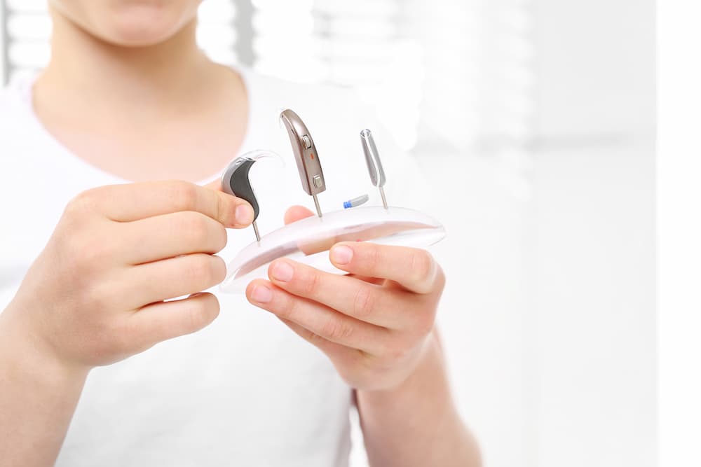 Person holding different kinds of hearing aid styles